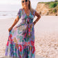 woman at the beach wearing a floral leaf print flutter sleeve with tie front maxi dress in purple