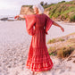 woman at the beach wearing an orange butterfly sleeves silk maxi dress