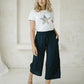 woman wearing a white top with star print and a Freez Sicily Shirred Waistband Loose Cropped Trousers with Pockets in ink color