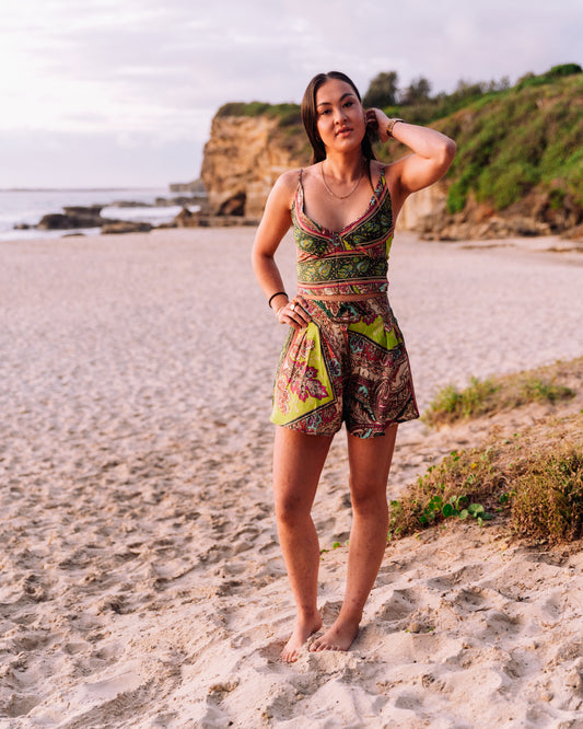 woman at the beach wearing a green paisley print cropped singlet top and shorts coordinates set
