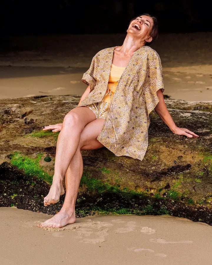 woman sitting on a rock on the beach wearing Arabesque Short & Kimono Set laughing