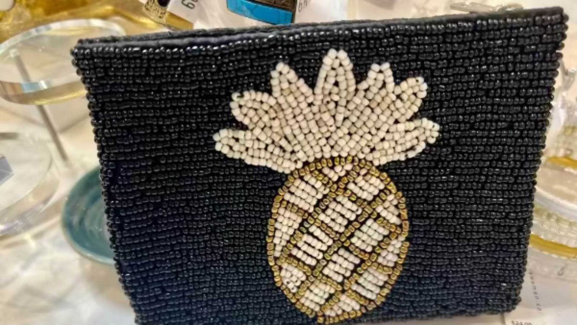 Black beaded clutch with a pineapple design on a reflective surface