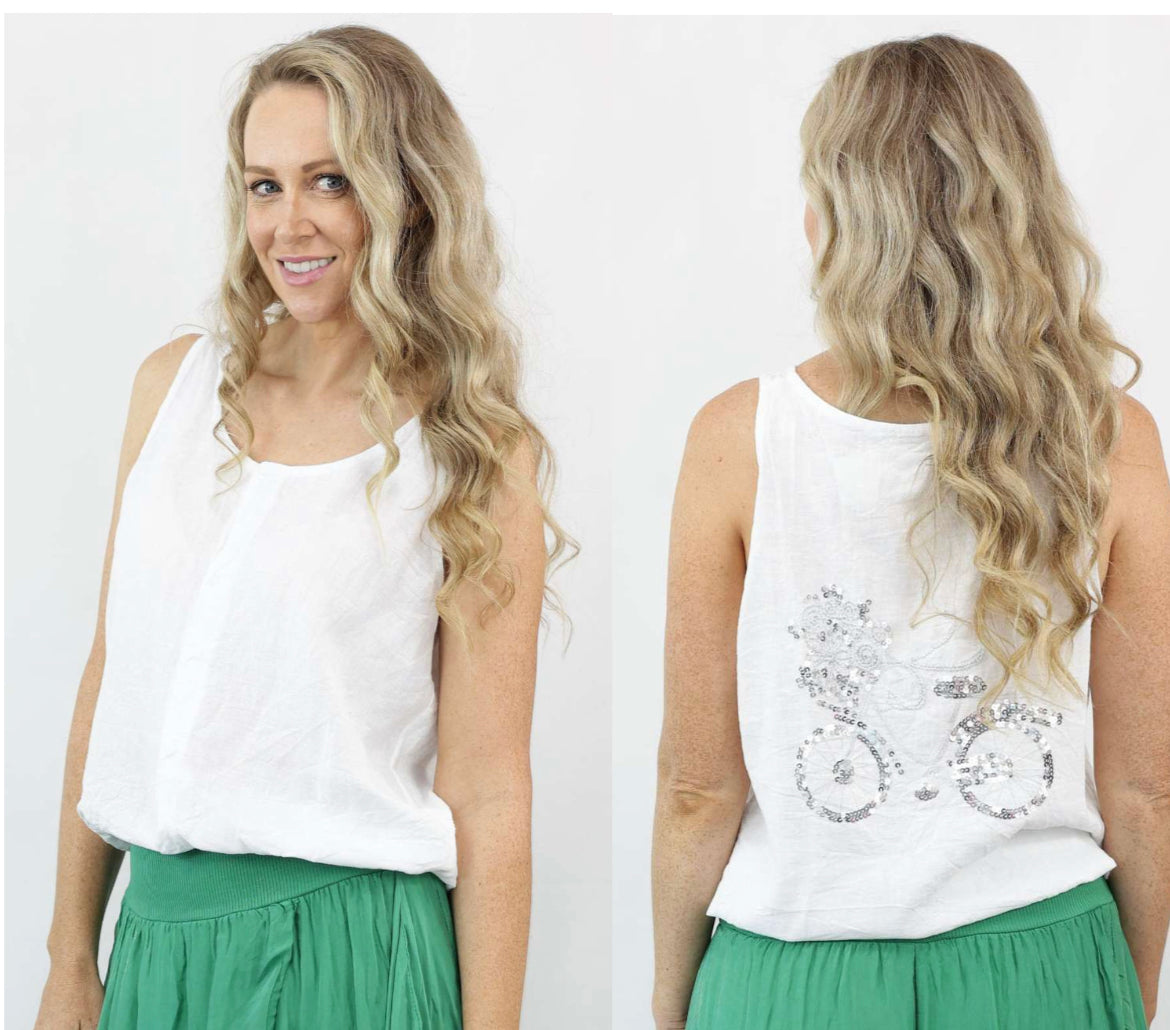 woman wearing a white sleeveless linen button down top with sequined bicycle print at the back