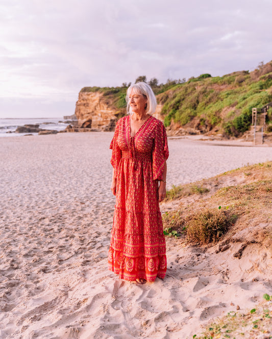 woman in the beach wearing a red butterfly sleeve tiered maxi dress