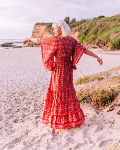 woman at the beach wearing an orange butterfly sleeves silk maxi dress