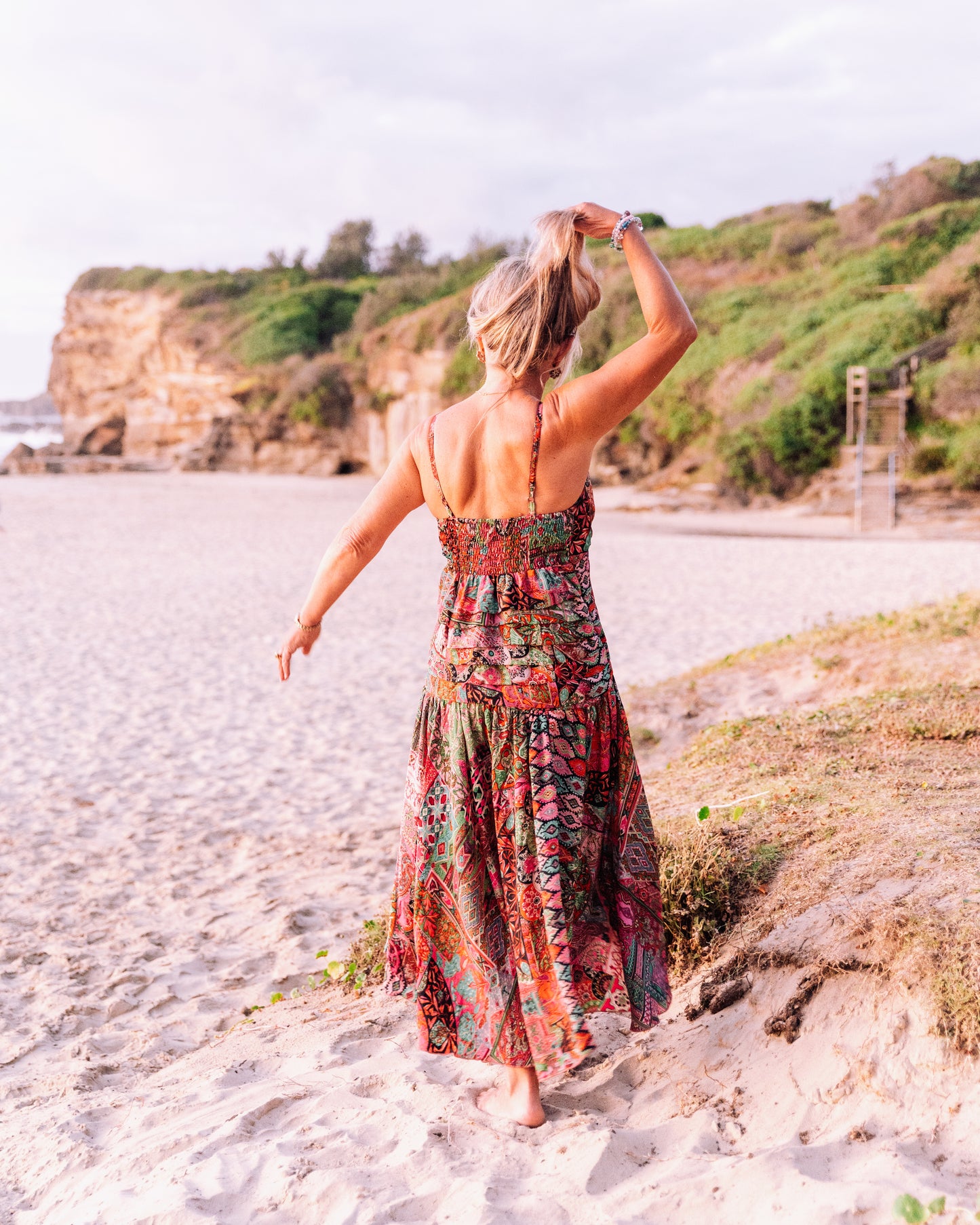 woman in the beach showing her back and wearing a ruffled silk singlet maxi dress