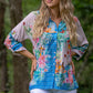 woman standing wearing a tropical floral butterfly print long sleeve button down shirt - light pink and blue
