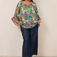woman wearing a parrot tropical print top with tie neck tassel