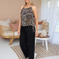 woman wearing a leopard spag strap top and black smocked waist pants