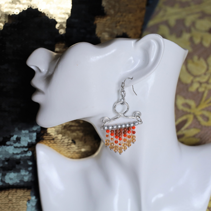 fringe seed beads chandelier hook earrings in brown orange color dangling on a mannequin