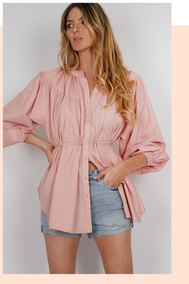 woman wearing a mandarin collared balloon sleeve cinched waist button down shirt in blush rose pink