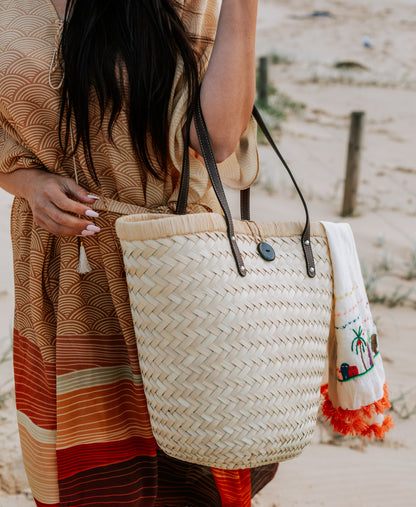 woman wearing Amera Eid Kaftan - Layali Design with a straw bag