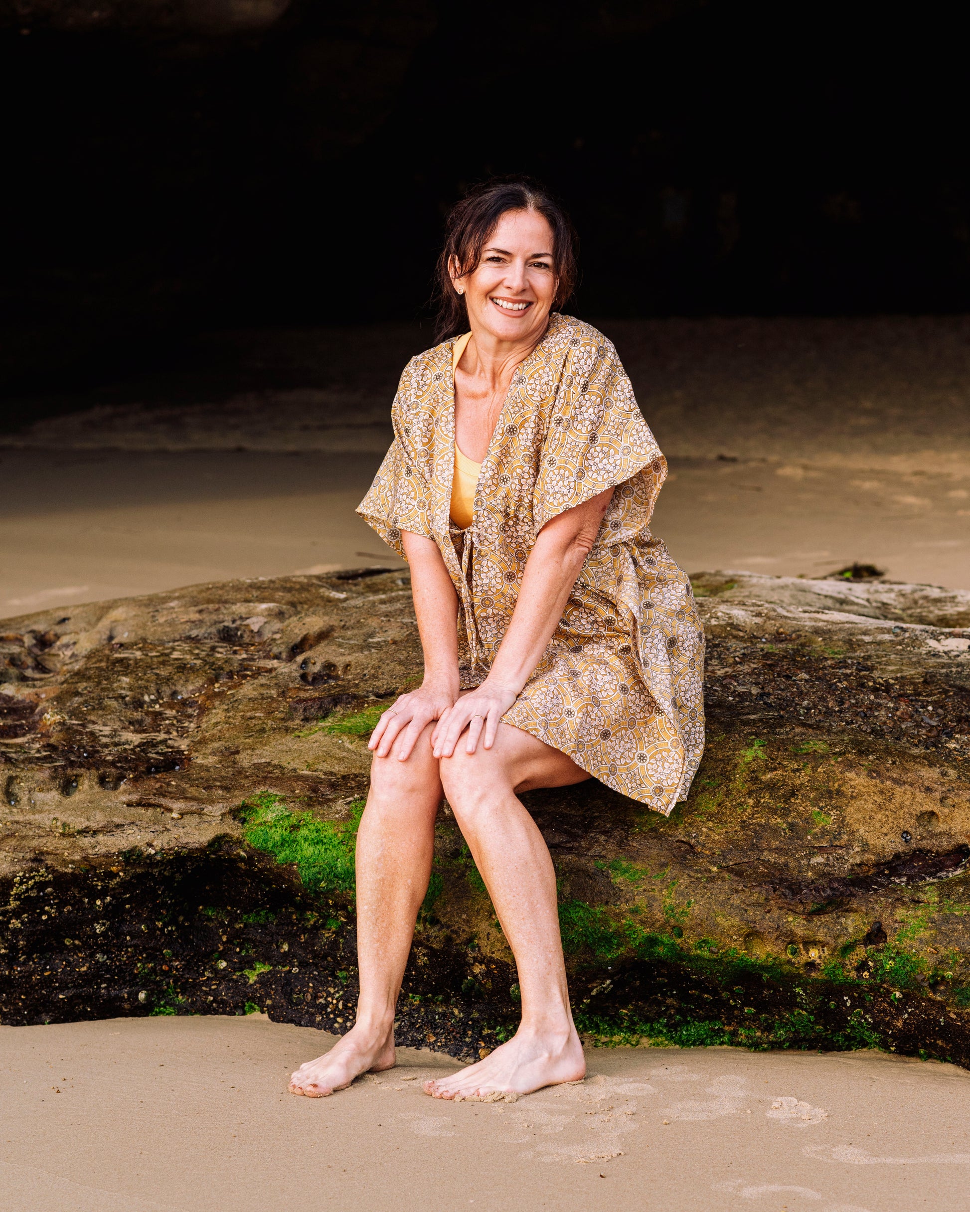 woman sitting at the sea side on a rock wearing a Penelope Arabesque Shorts & Kimono Set