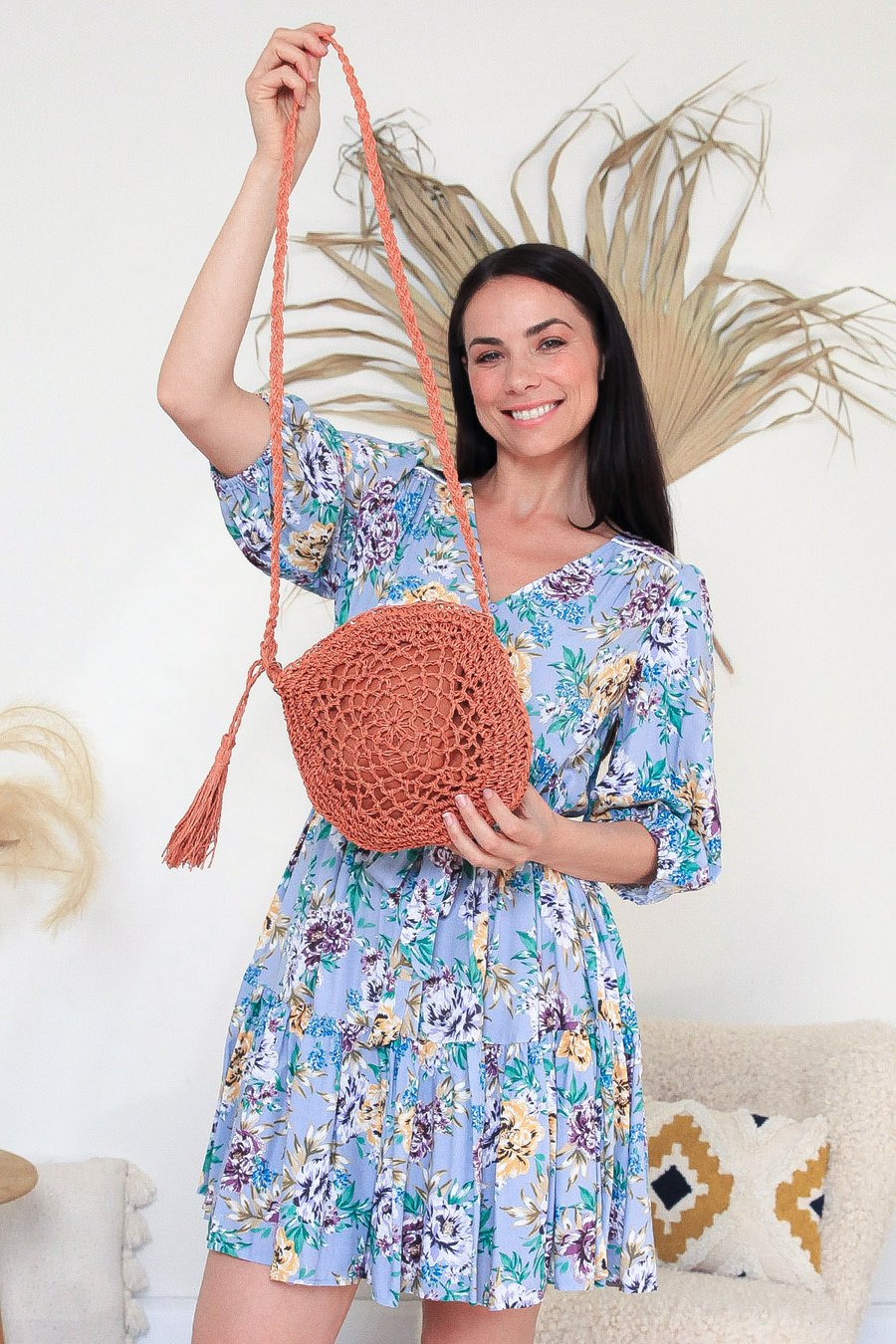 woman wearing a floral dress paired with a rust French Straw Woven Round Shoulder Bag with Tassel