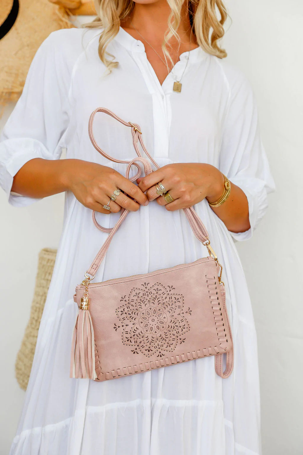 woman wearing white tiered dress with mandala cut crossbody bag with tassel in dusty pink