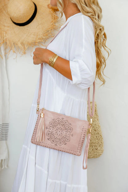 woman wearing white tiered dress with mandala cut crossbody bag with tassel in dusty pink