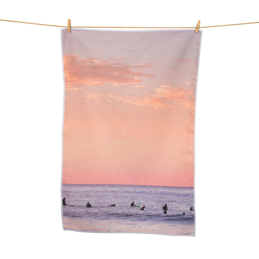 morning lineup tea towel with surfers at the beach sunset