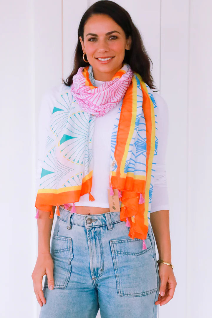 woman wearing white top with isabella abstract orange scarf with tassels wrapped on neck