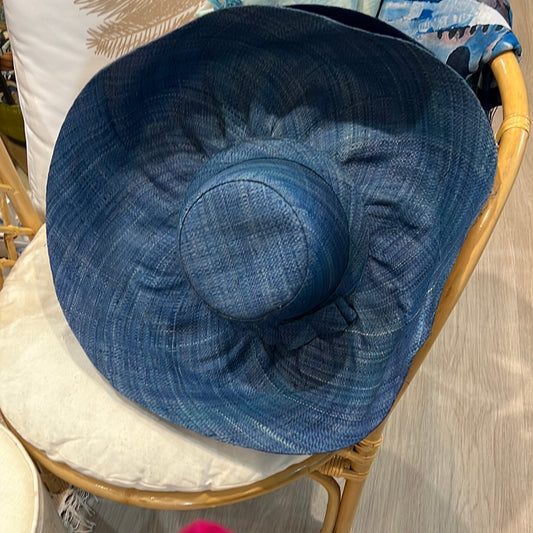 blue wide brim woven straw hat with ribbon bow on a chair