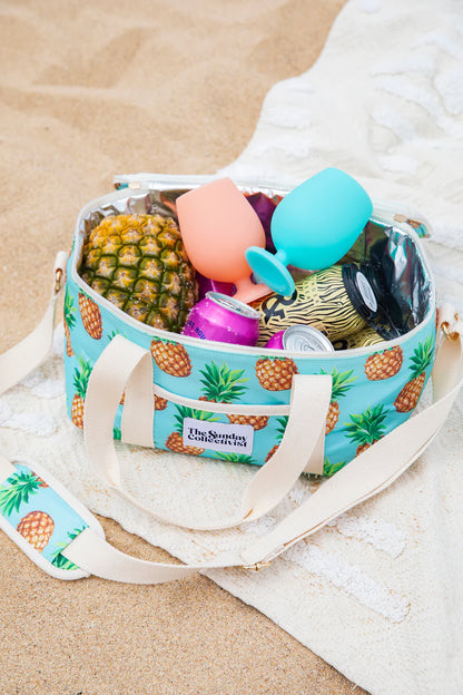 Collapsible Cooler Bag in Pineapple Print by The Sunday Collectivist - PACIFICA 32cm X 20cm X 17cm on a beach sand with towel