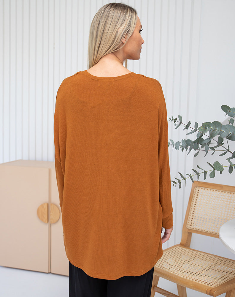 woman wearing freez cape shrug in henna color back view