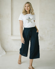 woman wearing a white top with star print and a Freez Sicily Shirred Waistband Loose Cropped Trousers with Pockets in ink color