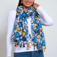 woman wearing white long sleeve and a blue yellow circle pattern scarf with tassels 